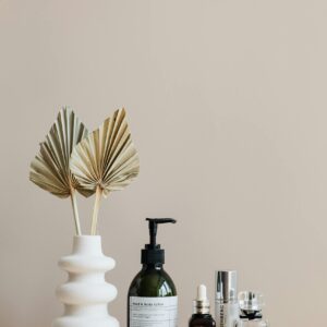 Minimalist bathroom shelf featuring skincare bottles and decorative beige vase.